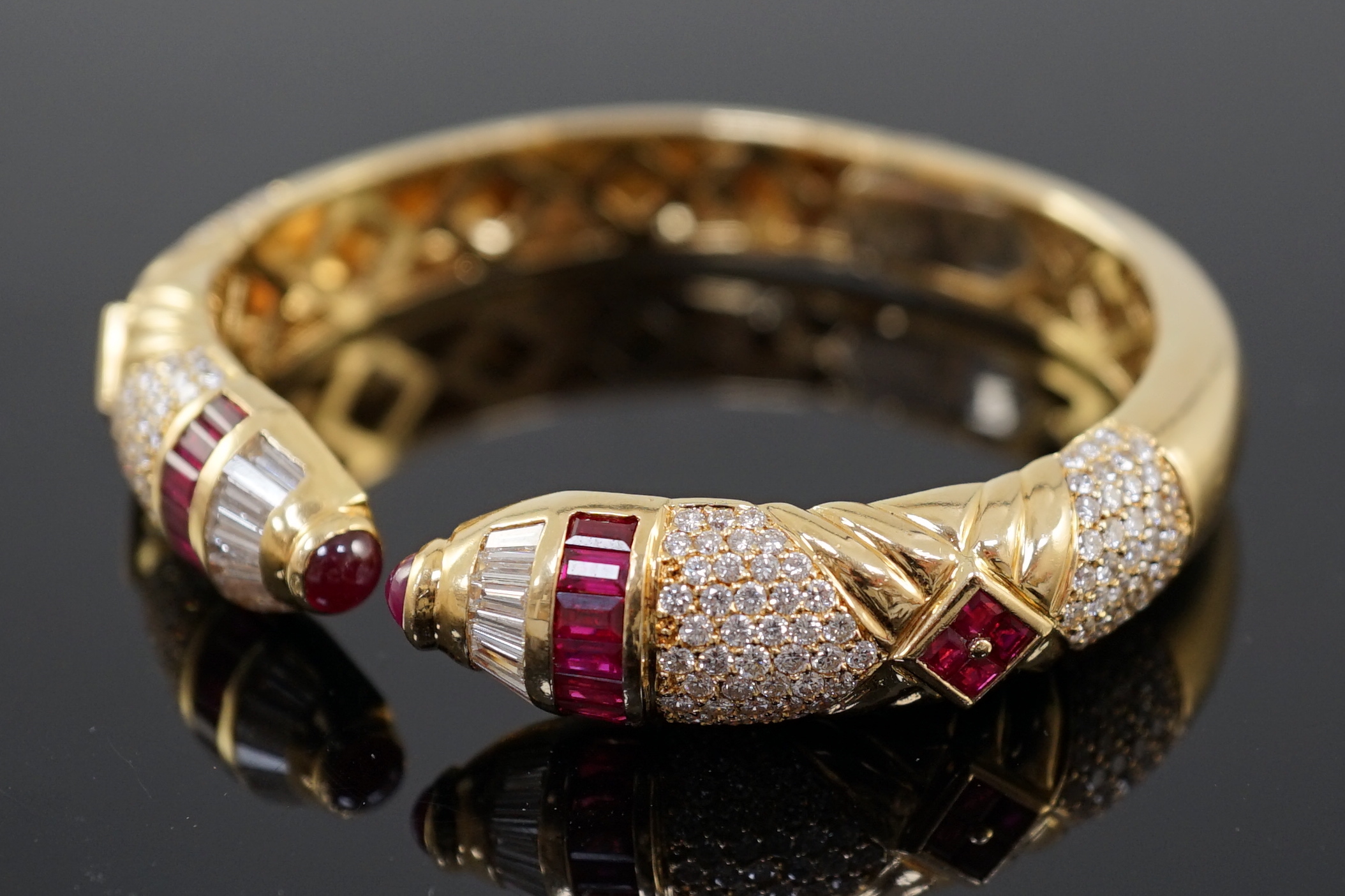 A modern 18ct gold, ruby and diamond cluster openwork hinged bangle